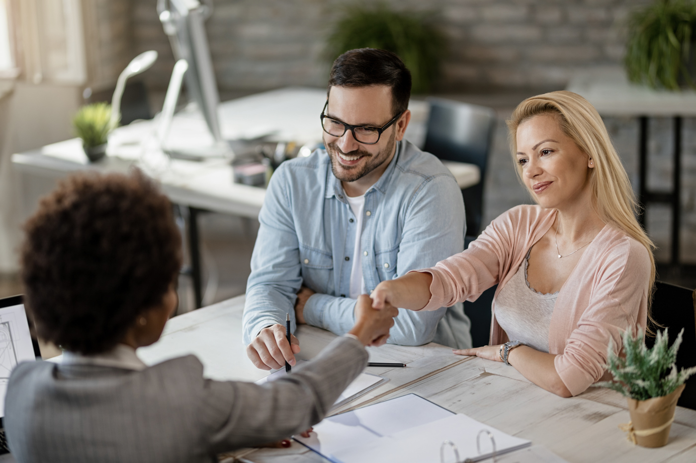 Business owners shake hands with an advisor during a small business grants Canada meeting