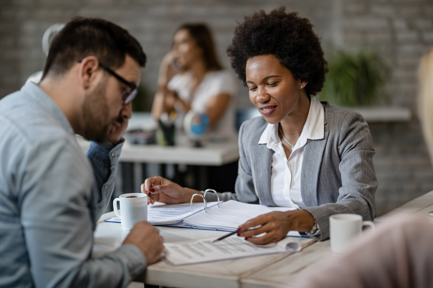 Professional woman reviewing loan documents with clients at a desk, discussing women in business grants Canada