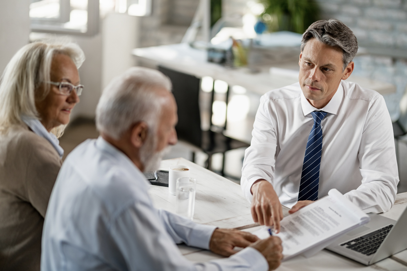 Professionals reviewing loan documents at a table during a business funding meeting
