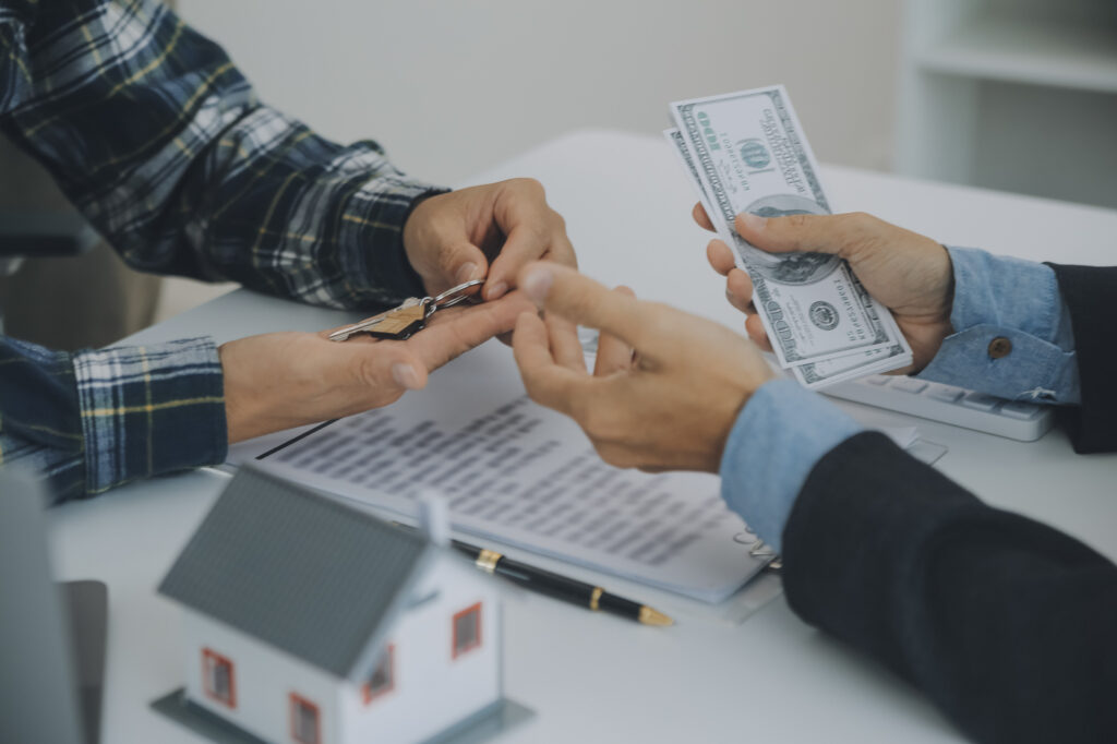 Hands exchanging keys and cash over documents, representing business funding or a second mortgage
